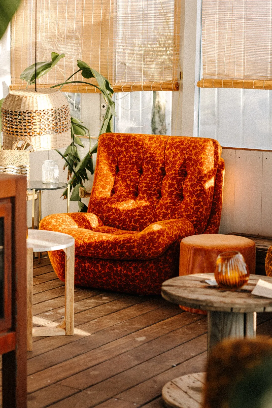 De lounge van NIUS met een oranje fluwelen fauteuil, planten en kaarslicht bij het raam