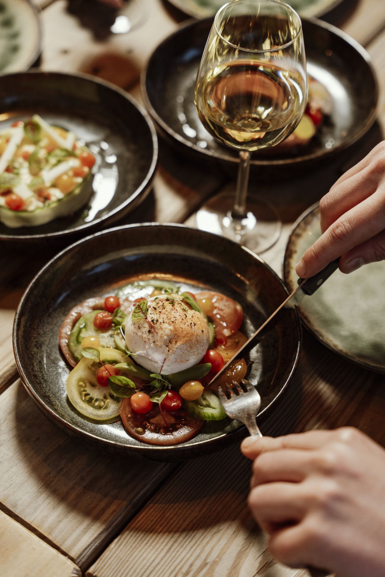 Borden met burrata en een glas witte wijn op een houten tafel
