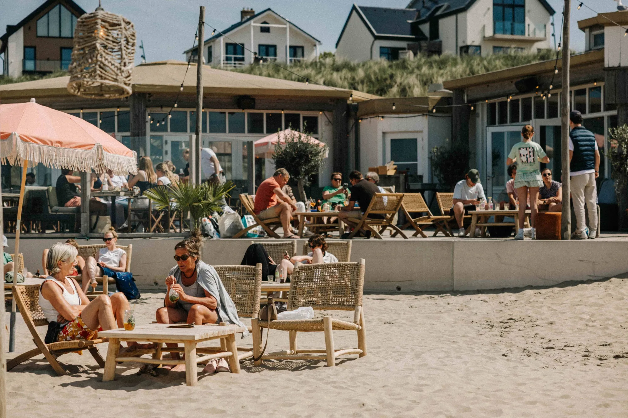 Gasten in strandstoelen op het zand voor NIUS in de zomer