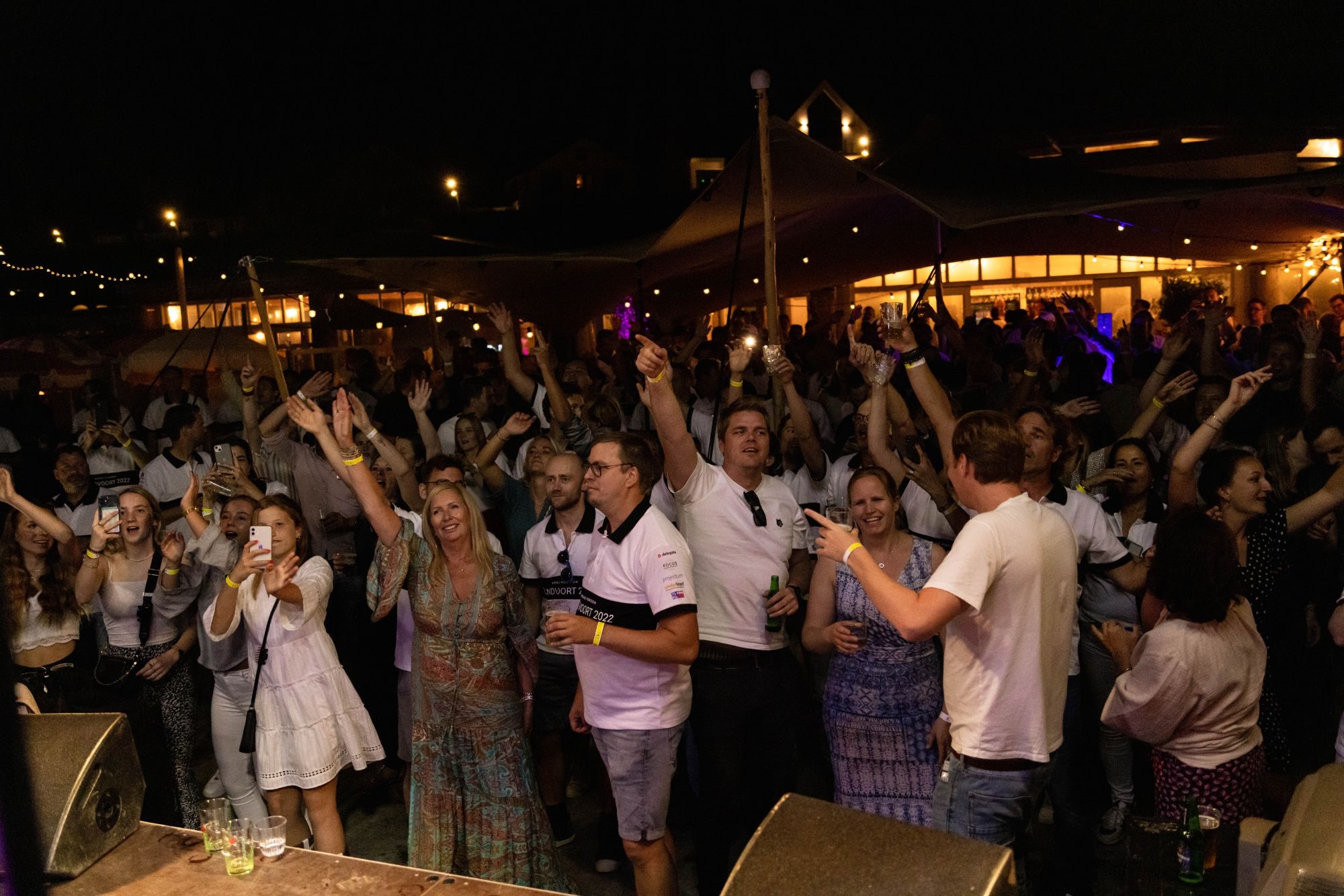 Een grote groep feestende gasten in de avond bij NIUS