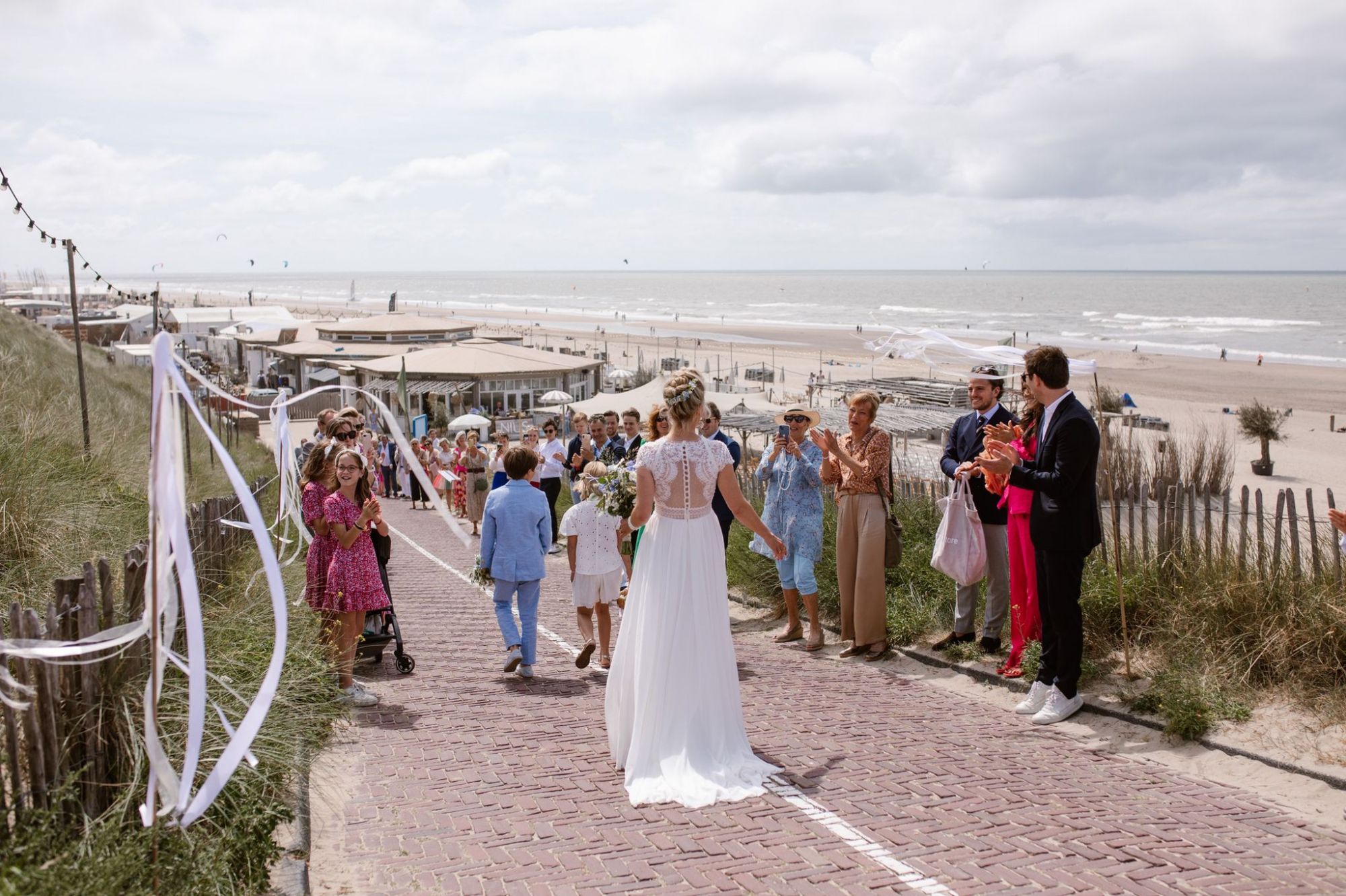 Het bruidspaar loopt met de gasten de strandafgang af naar NIUS